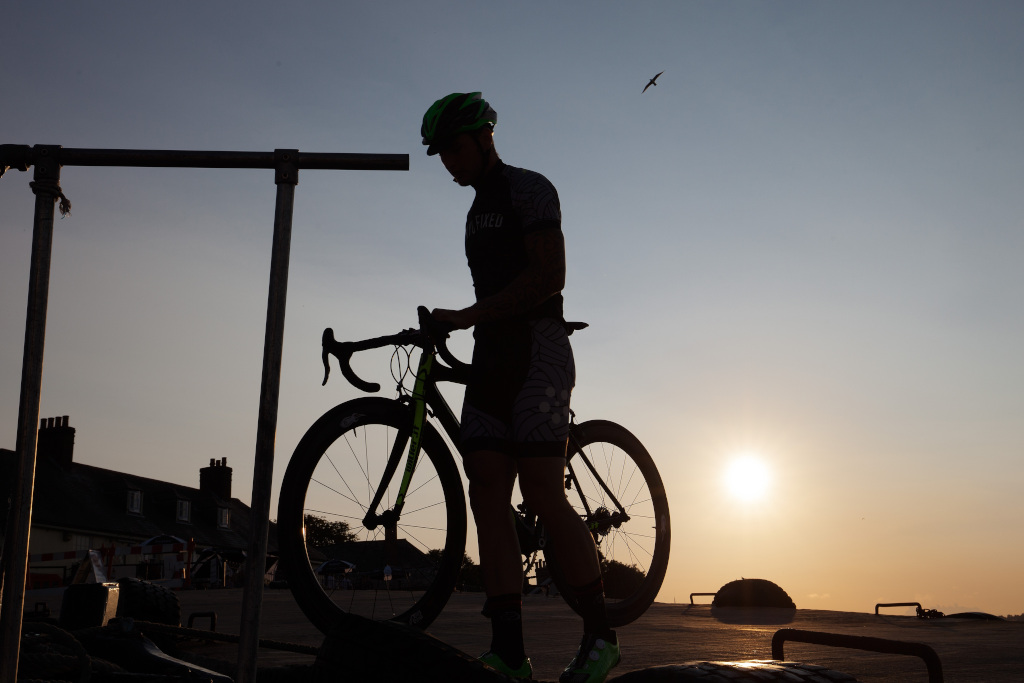 Ciclista in penombra mentre posa la sua bici